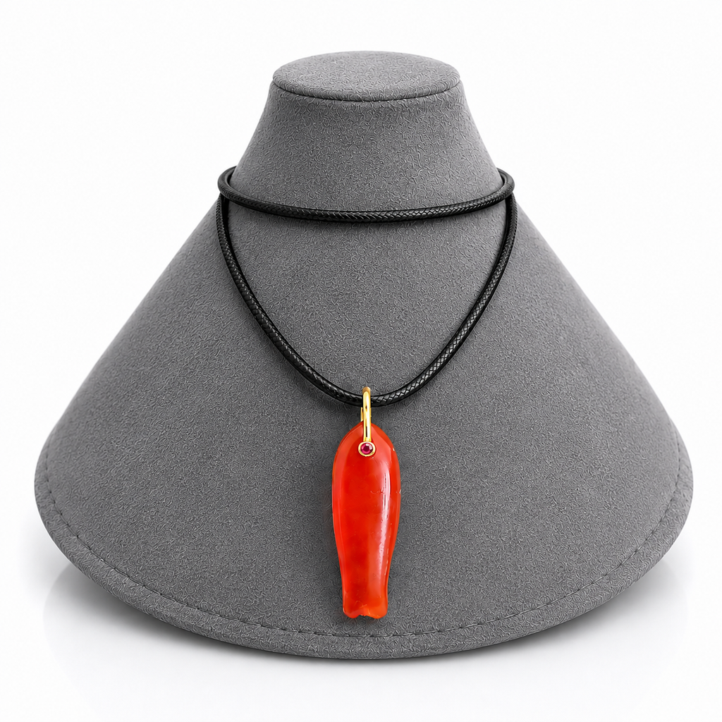 A red carved pendant necklace with a gold-colored loop and black cord, displayed on a gray jewelry bust against a white background.